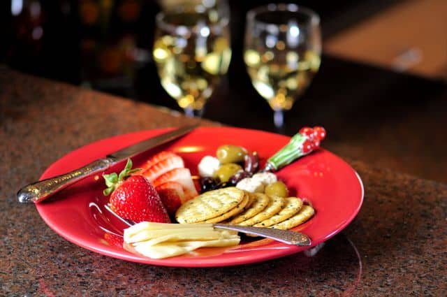 Elegant platter with cheese, crackers, strawberries, and wine, ideal for dining settings.