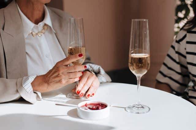 Close-up of two people with champagne glasses at a round table during a social gathering.